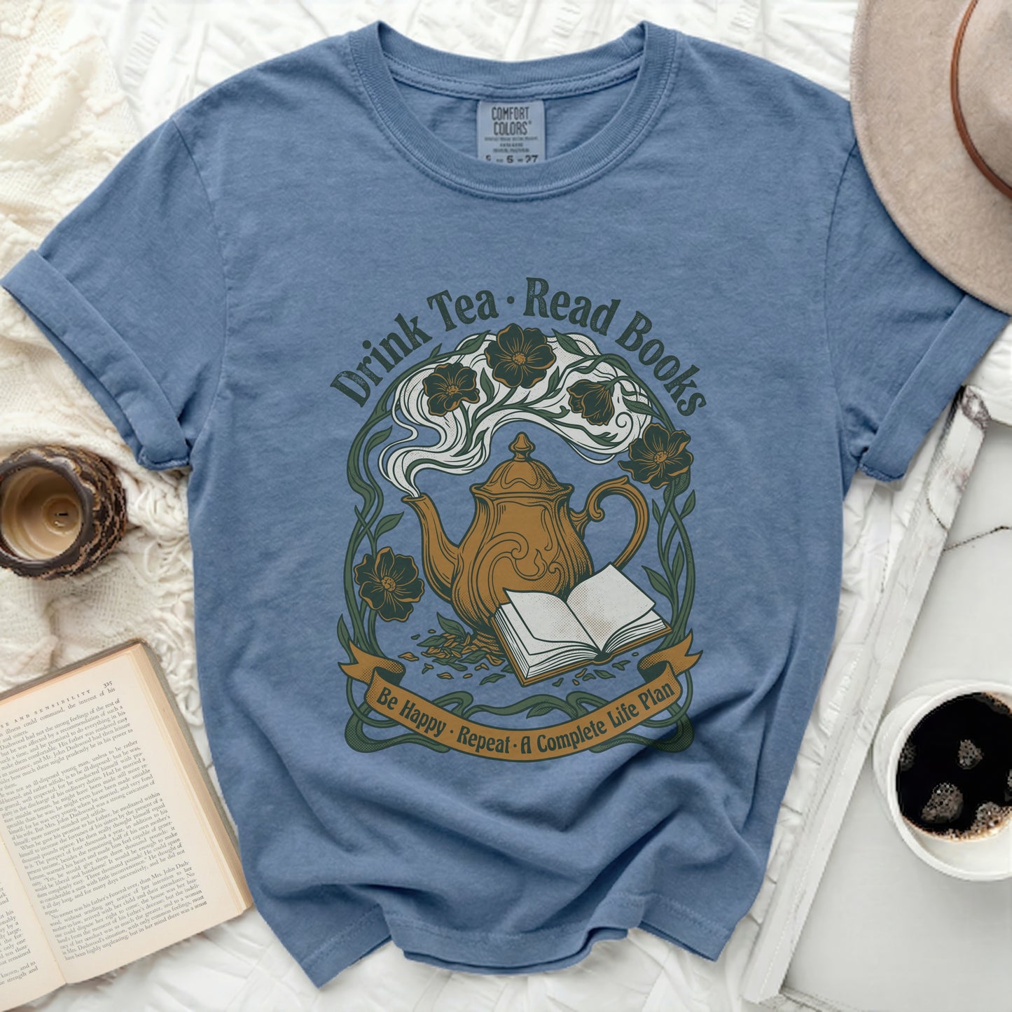 Blue t-shirt with "Drink Tea, Read Books, Be Happy, Repeat" text and teapot design.