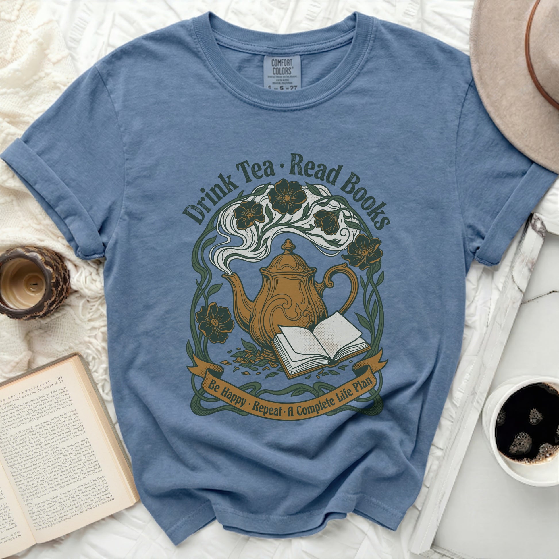 Blue t-shirt with "Drink Tea, Read Books, Be Happy, Repeat" text and teapot design.