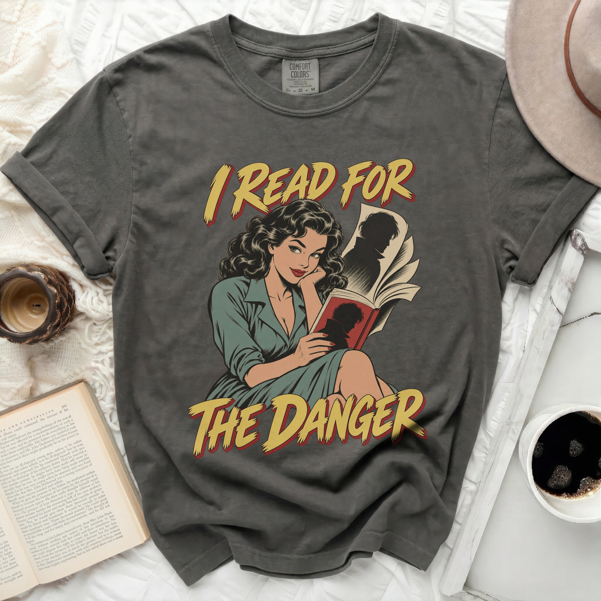Gray t-shirt with a comic illustration of a woman reading, text "I READ FOR THE DANGER".