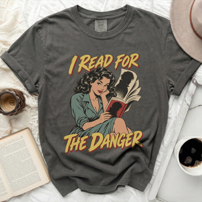 Gray t-shirt with a comic illustration of a woman reading, text "I READ FOR THE DANGER".