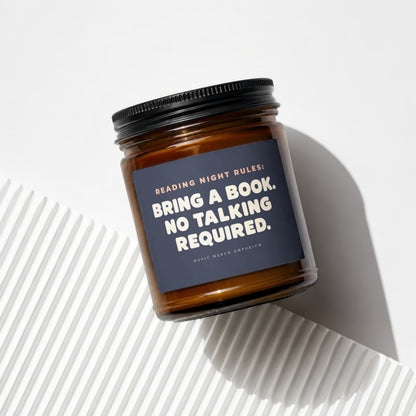 Amber jar candle with dark blue label reading "Reading Night Rules: Bring a Book. No Talking Required."