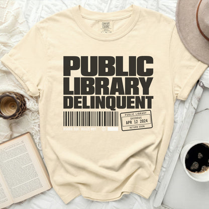 Cream t-shirt with "Public Library Delinquent" text and a library card graphic.