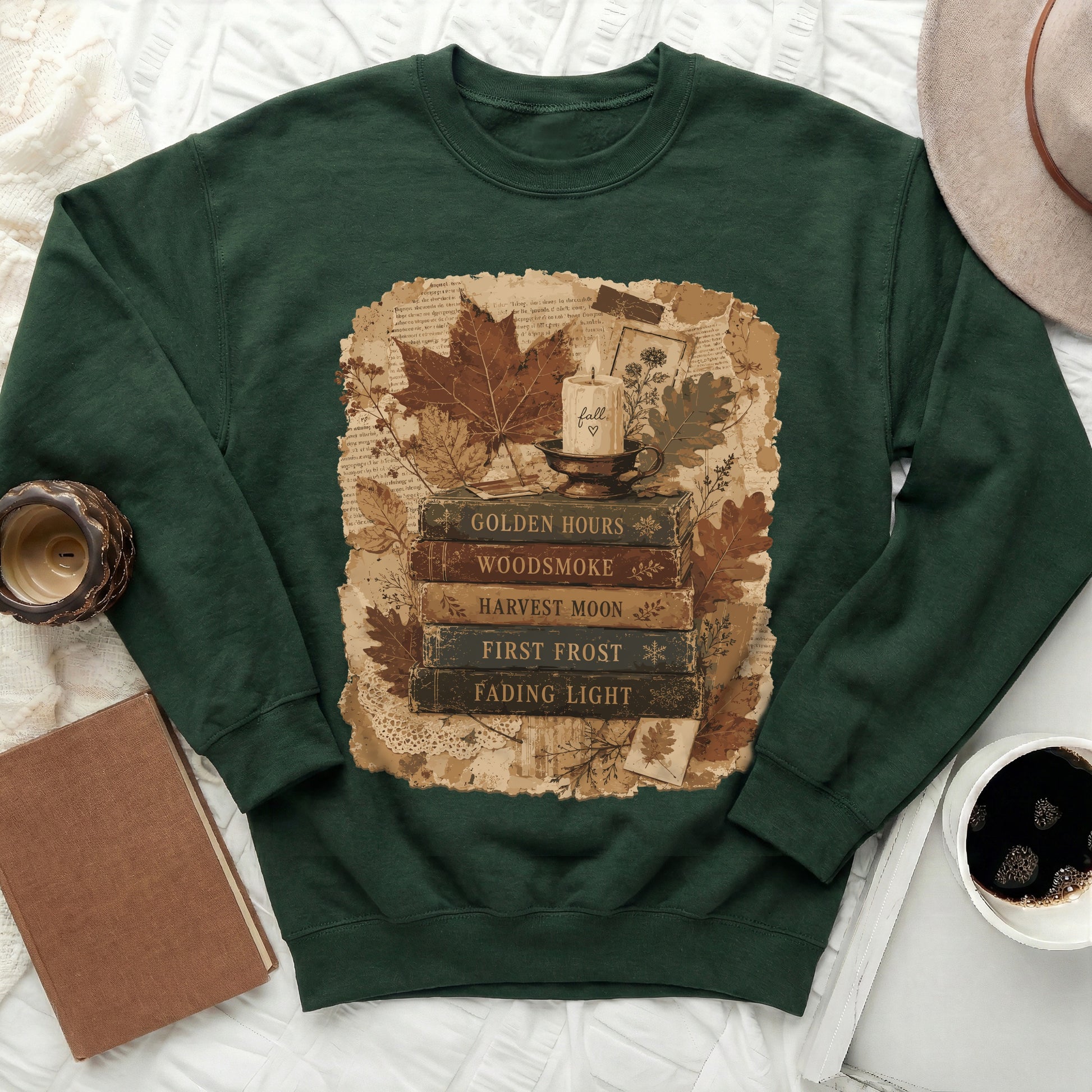 Green sweatshirt with fall-themed graphic of stacked books, candle, and leaves.