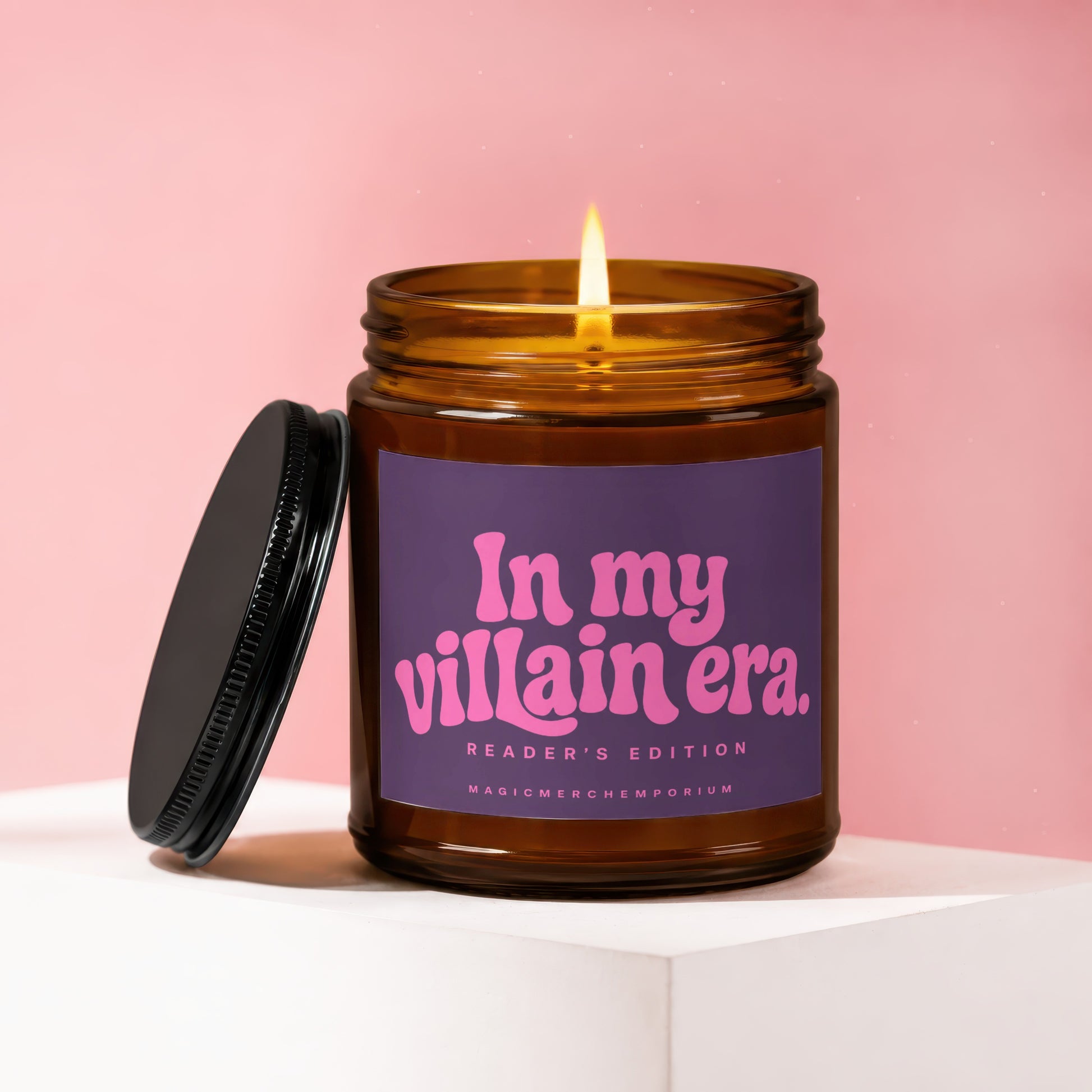 Brown glass candle from MagicMerchEmporium with lit flame, reads "In my villain era. READER'S EDITION".