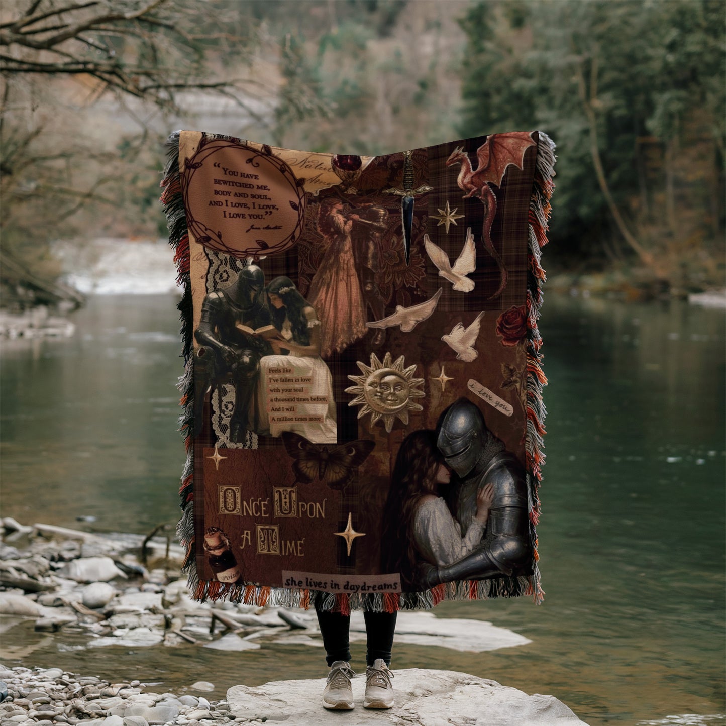 A person is standing on a rock, holding a large blanket with various images and text printed on it, including a quote and a fairy tale-like scene.