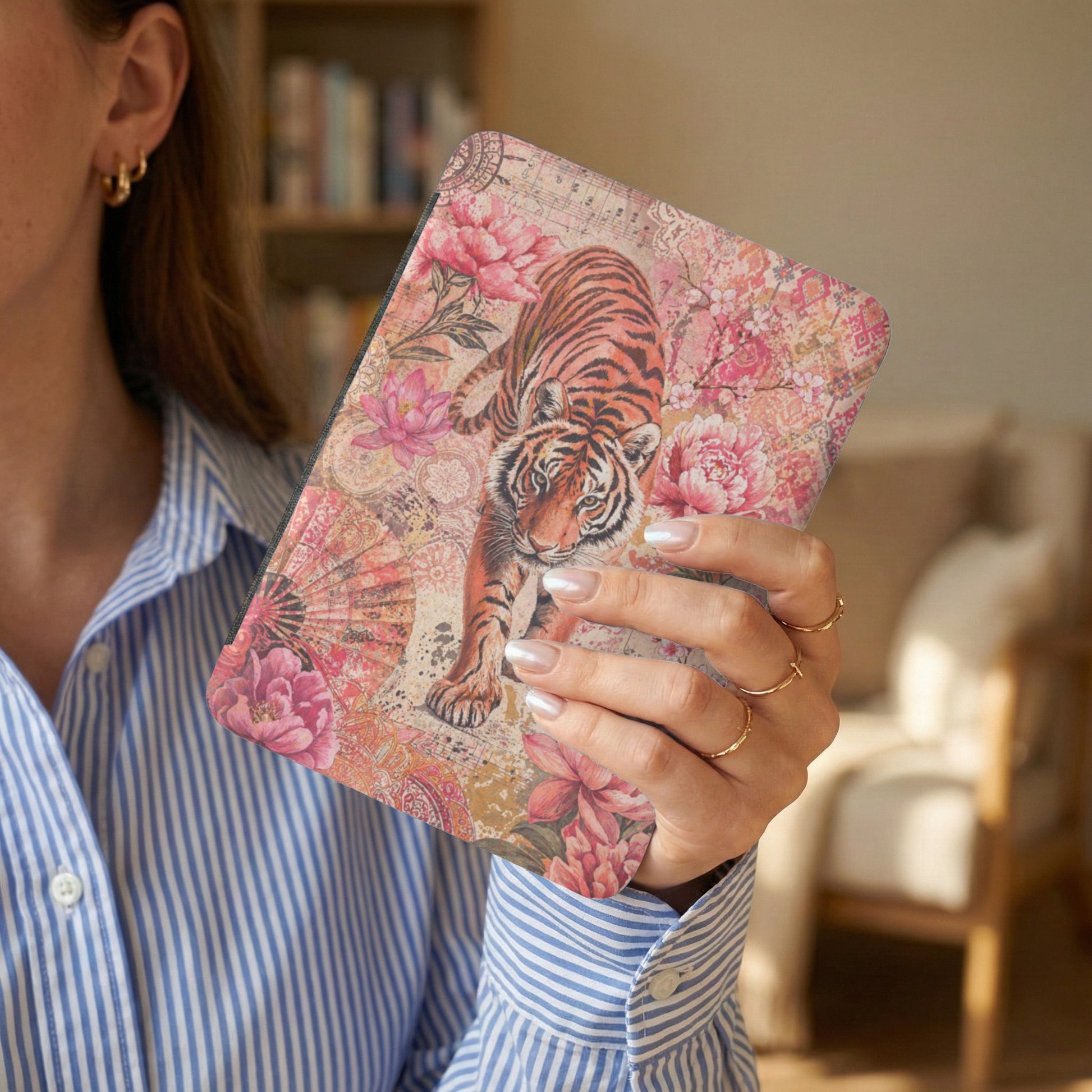 Book cover with a tiger, pink flowers, and ornate patterns, held by a woman.