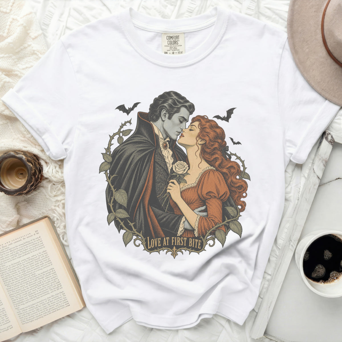 White t-shirt with gothic vampire couple and bats graphic that says "Love at First Bite."