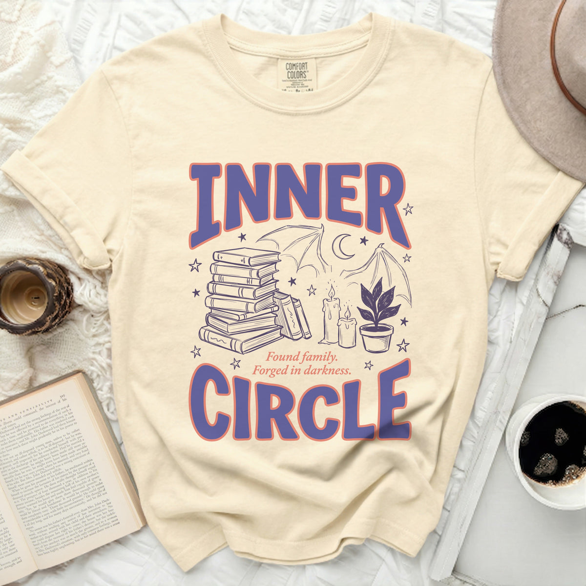 Cream t-shirt with "INNER CIRCLE" text and graphic of books, candles, and bat wings.
