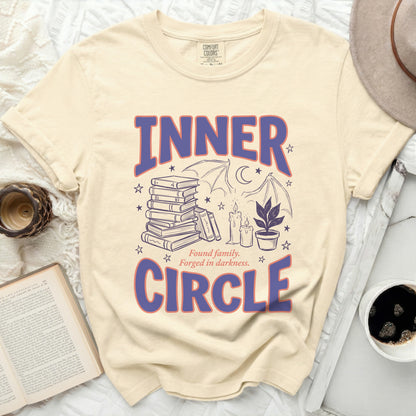 Cream t-shirt with "INNER CIRCLE" text and graphic of books, candles, and bat wings.