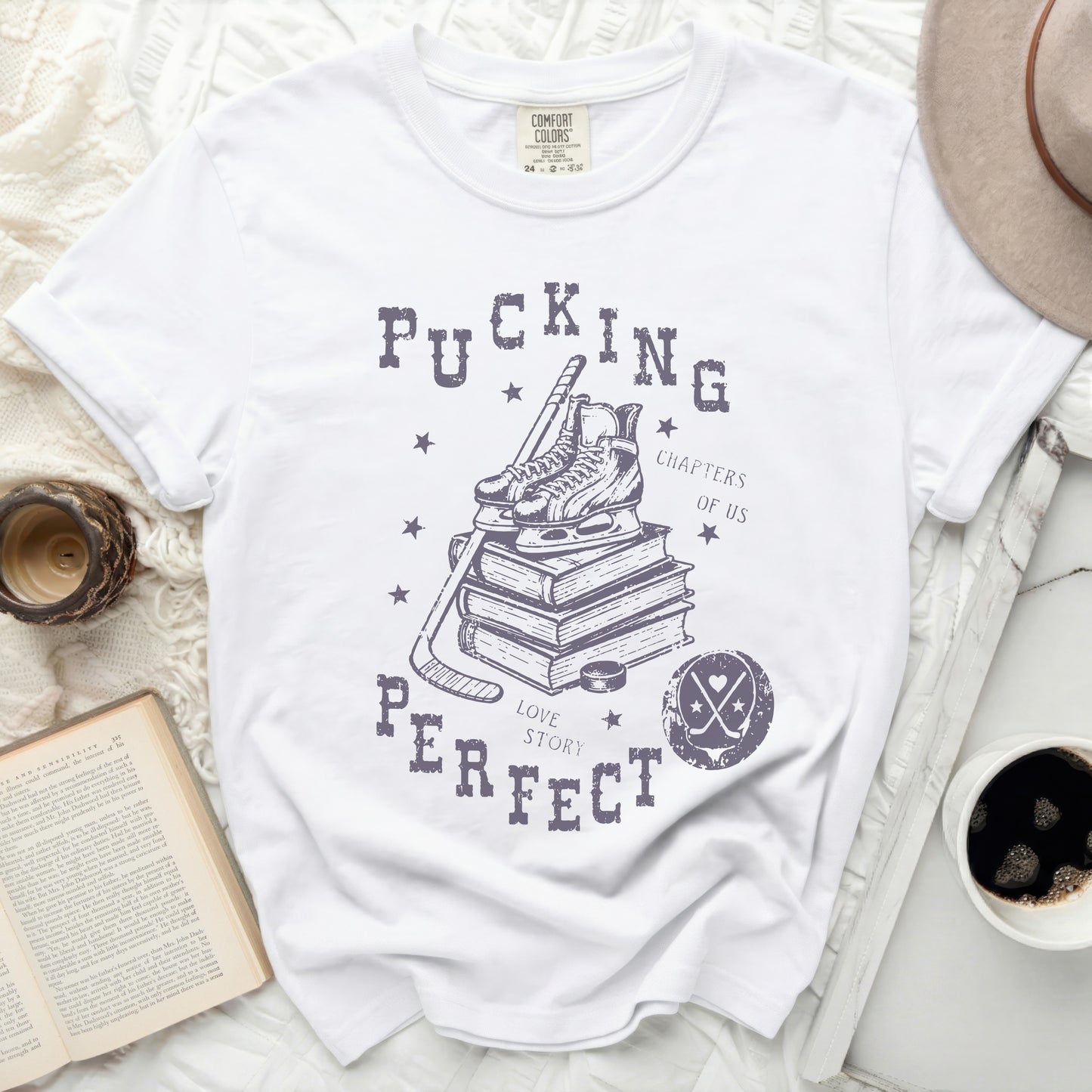 White graphic t-shirt with hockey skates, puck, and stack of books.