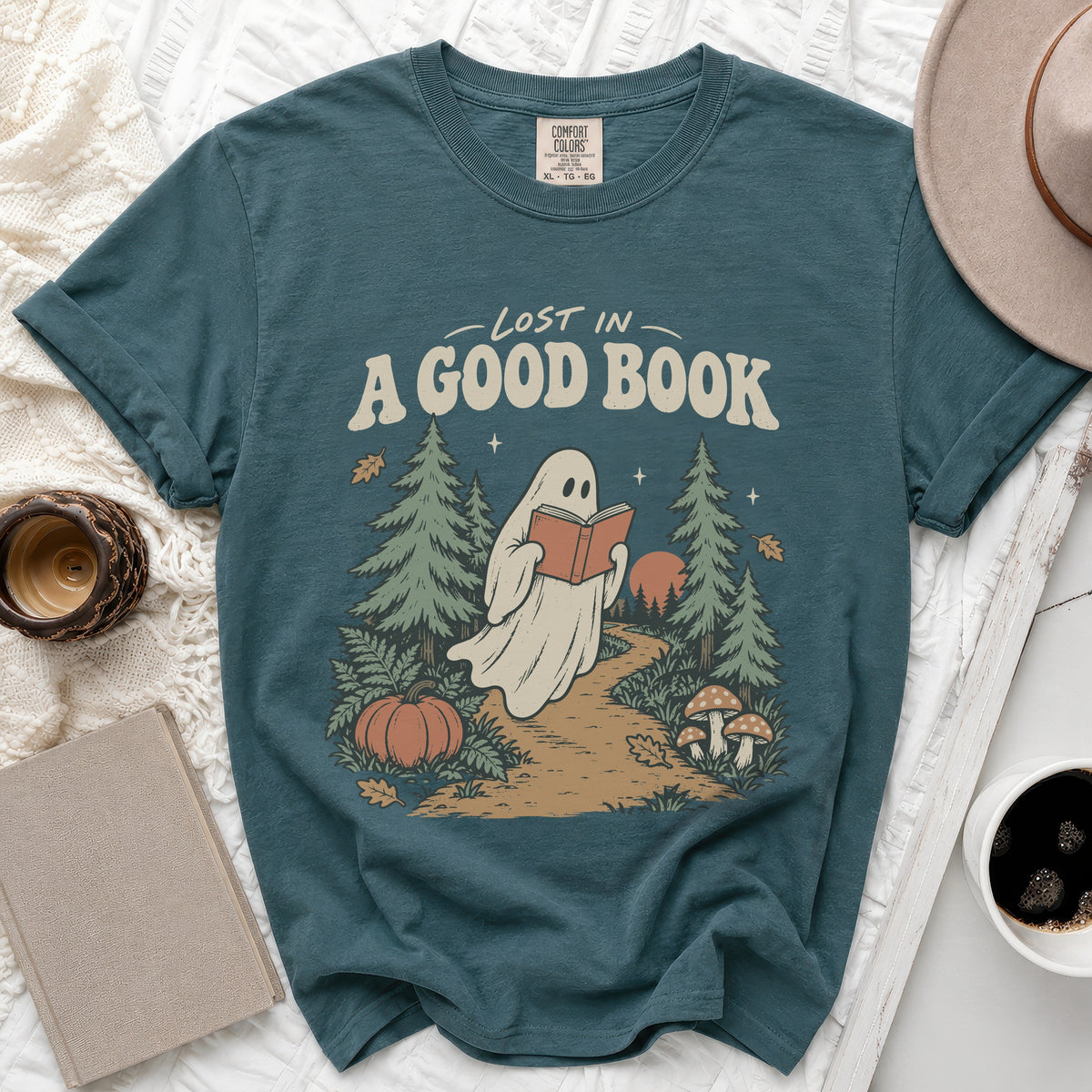Teal t-shirt with ghost reading a book in a forest, text "Lost in A Good Book".