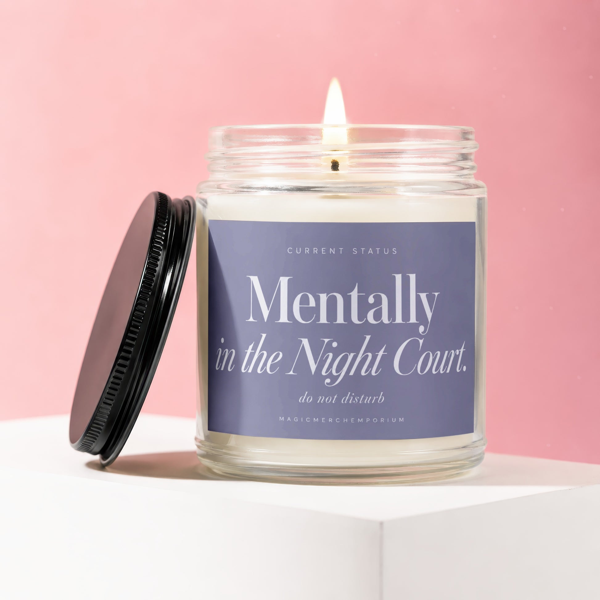 Lit candle in a glass jar with lavender label that says "Mentally in the Night Court."