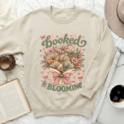 Light beige sweatshirt with "booked & blooming" text and book bouquet design.
