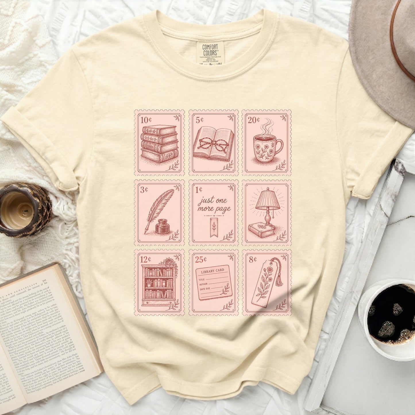 Cream t-shirt with pink book-themed icons and stamps.