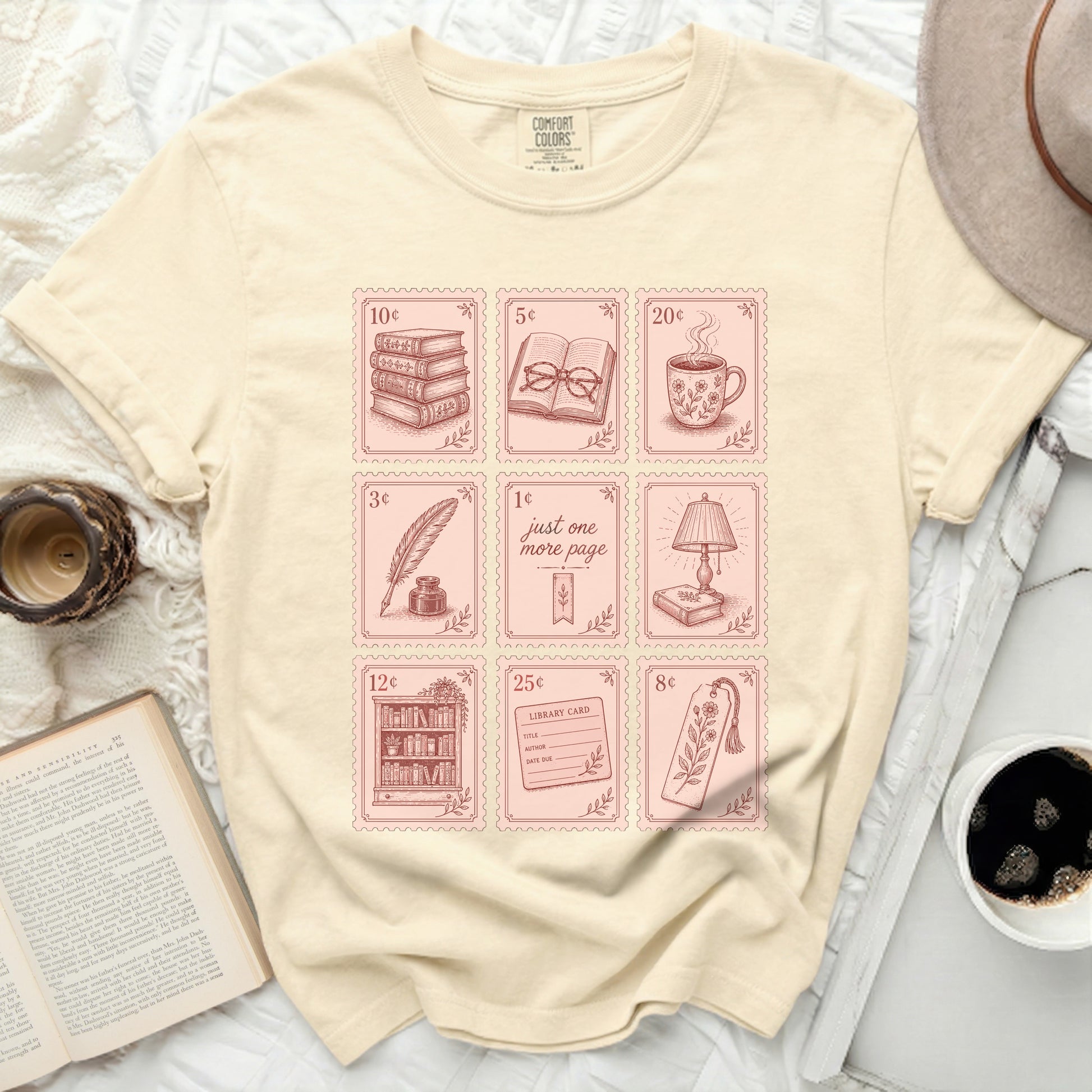 Cream t-shirt with pink book-themed icons and stamps.