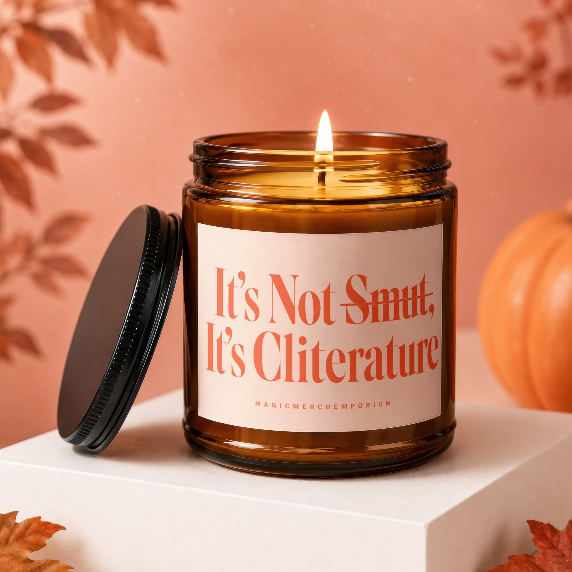 Amber glass candle with lit wick, reads "It's Not Smut, It's Cliterature".