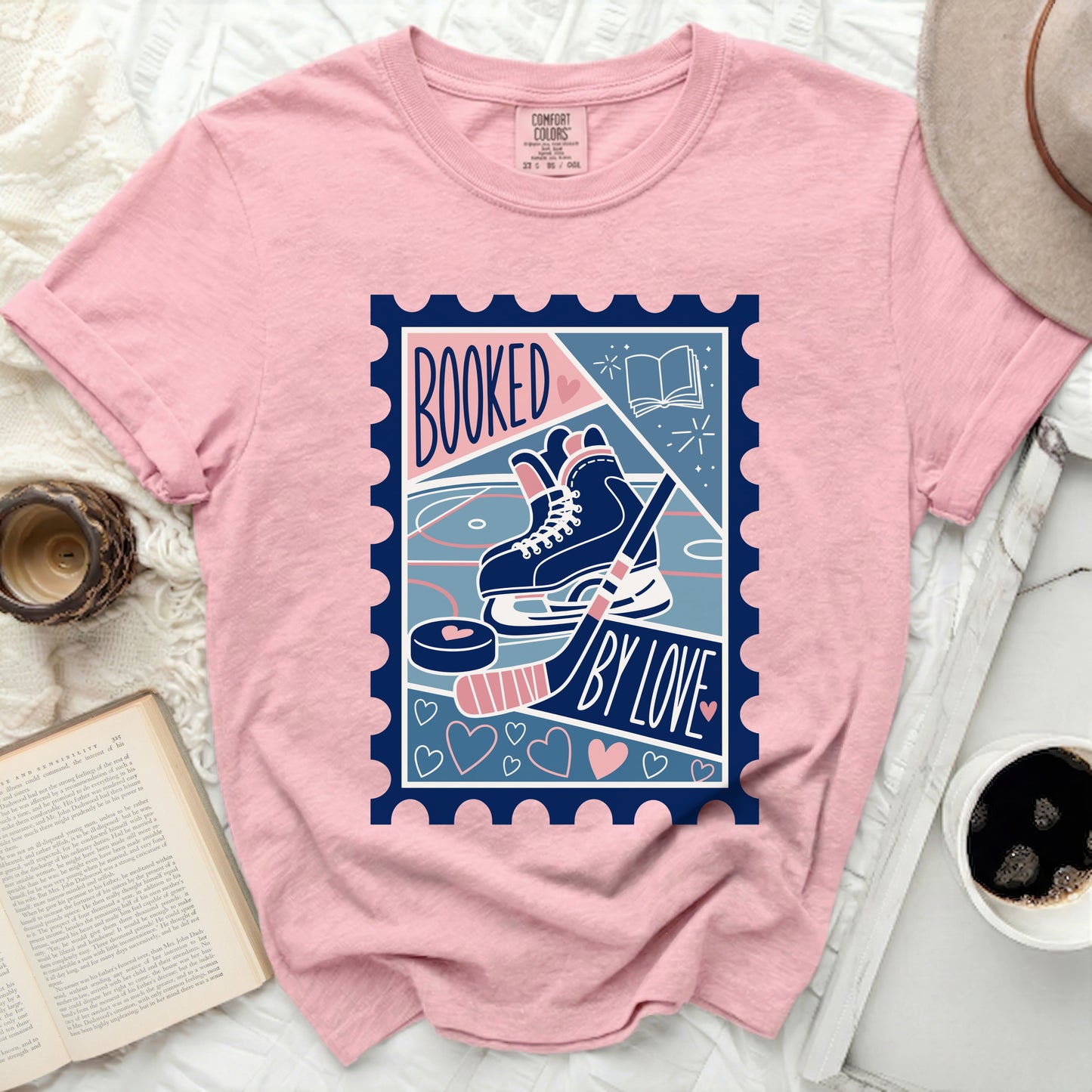 Pink t-shirt with "Booked by Love" stamp featuring hockey skates, puck, and book.
