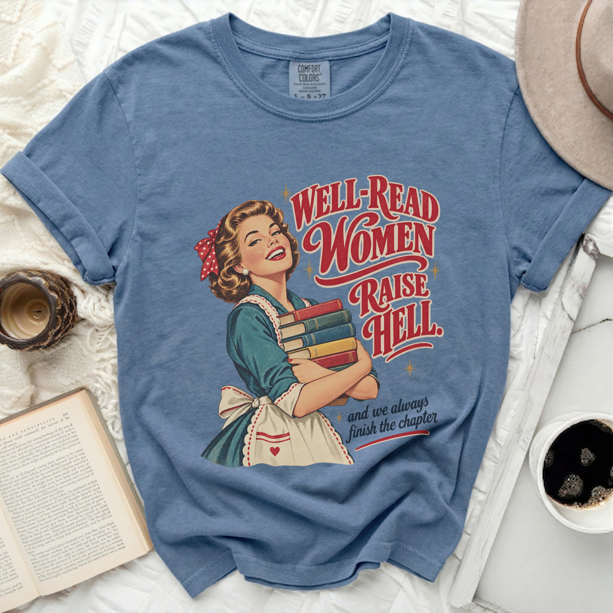 Blue t-shirt with retro graphic of a woman holding books, text "Well-read women raise hell".