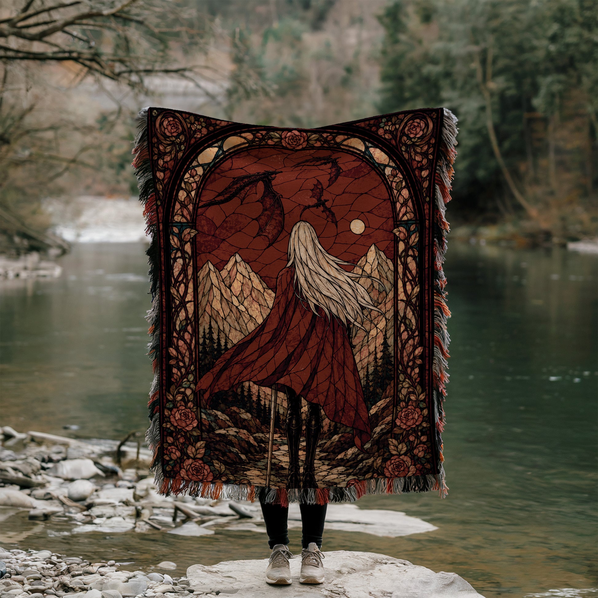 A person stands on a rock, holding a large, ornate blanket with a landscape design, including mountains, trees, and a river.