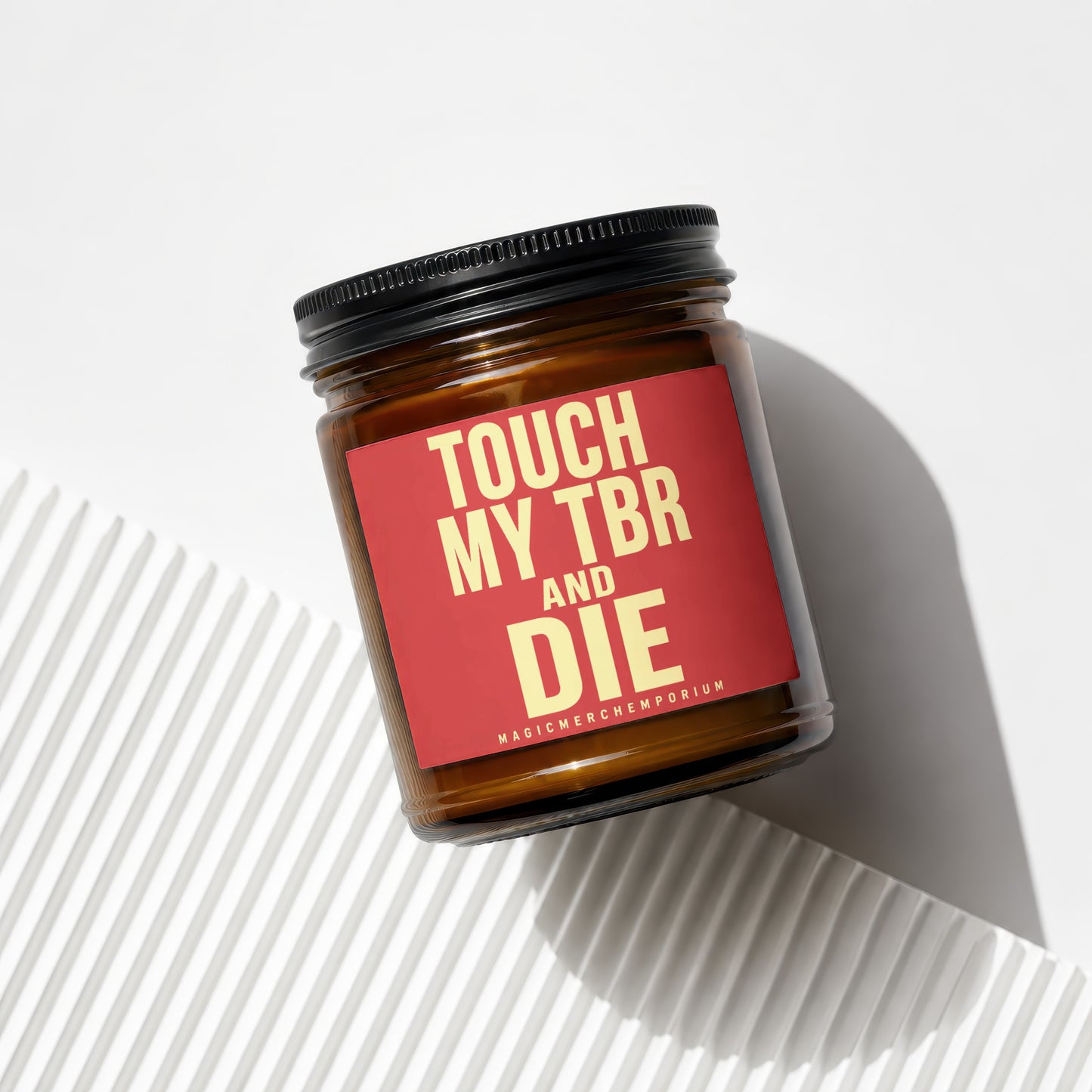 Amber glass candle with red label saying "TOUCH MY TBR AND DIE".