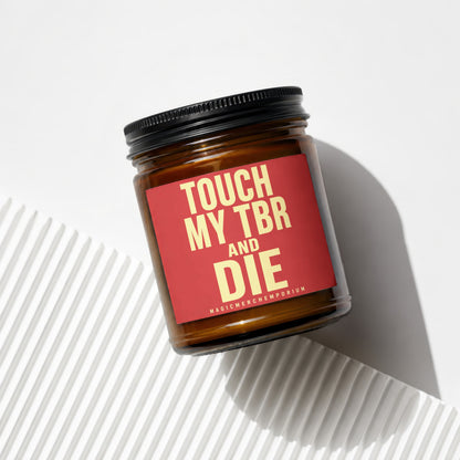 Amber glass candle with red label saying "TOUCH MY TBR AND DIE".