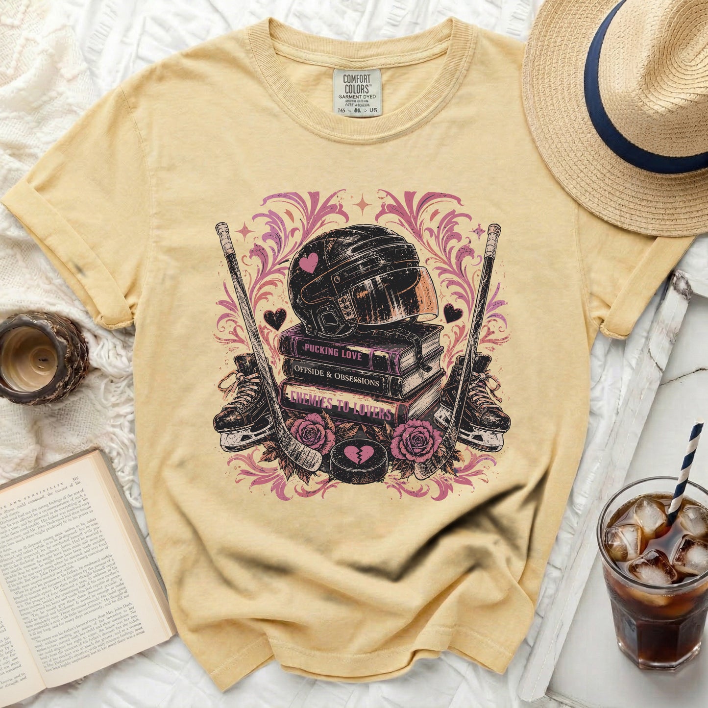 Yellow t-shirt with hockey helmet, skates, pucks, and pink hearts on books.