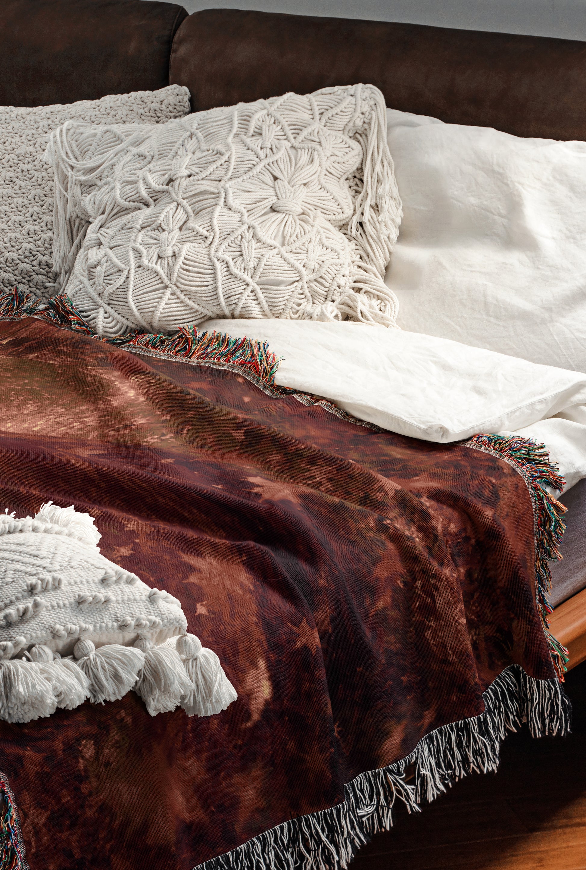 a cozy and inviting bedroom scene, featuring a comfortable bed with a brown blanket and white pillows, as well as a brown leather couch.