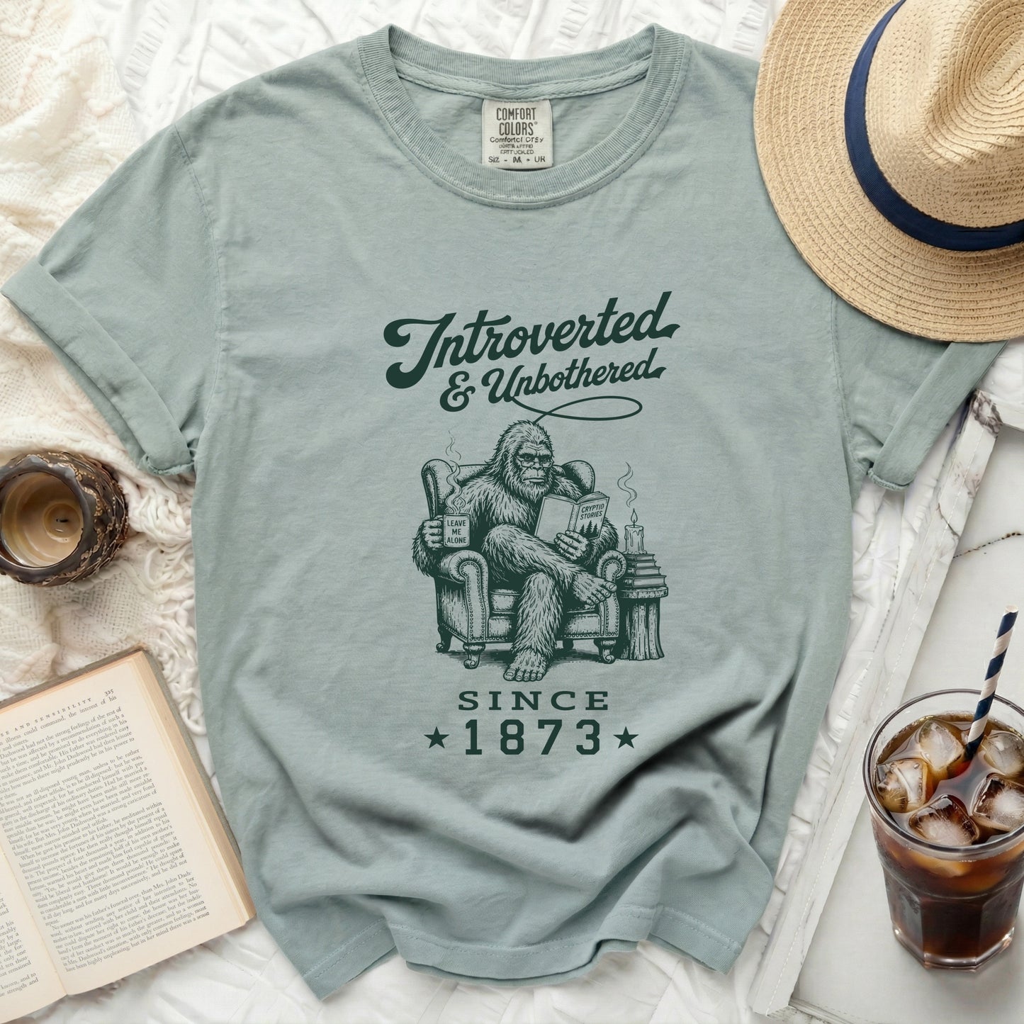 Beige t-shirt with "Introverted & Unbothered Since 1873" and Bigfoot graphic.