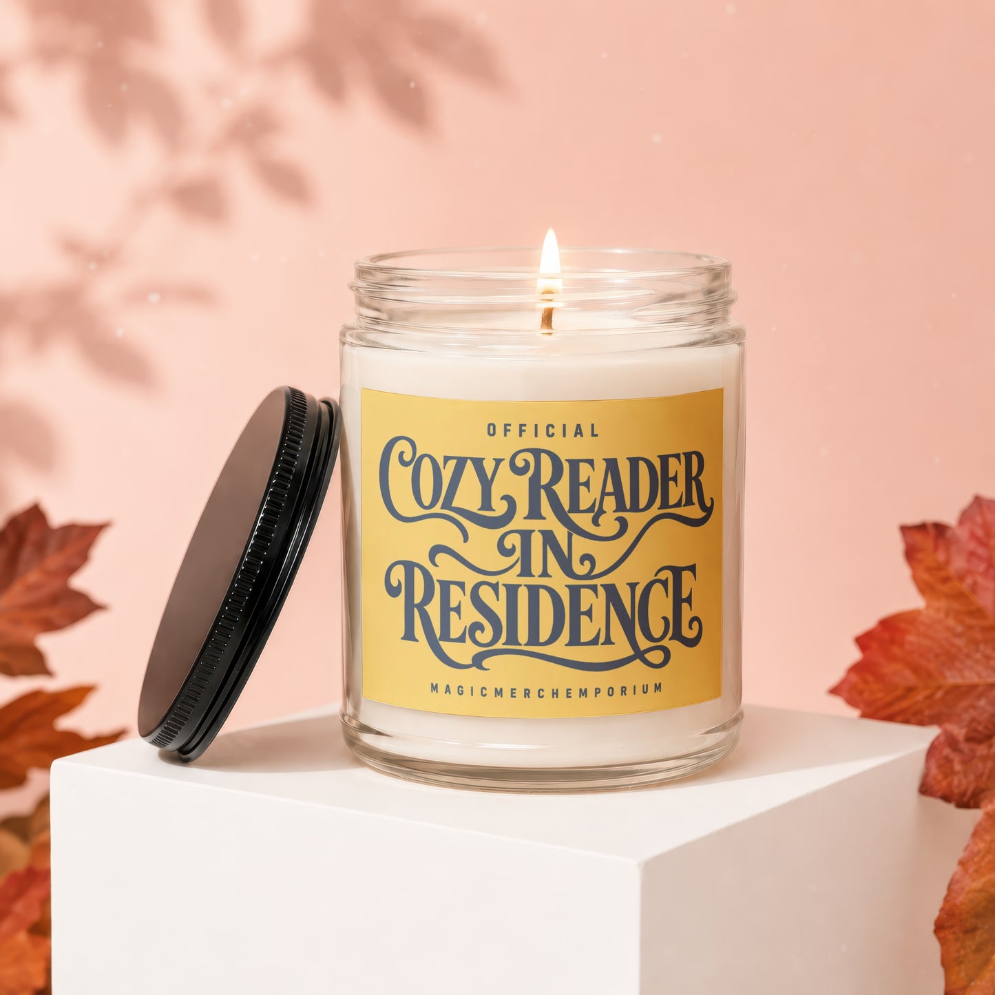 Candle with yellow label reading "Official Cozy Reader In Residence MagicMerchemporium".