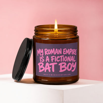 Amber jar candle with lit flame and lid askew, reads "My Roman Empire Is A Fictional Bat Boy".