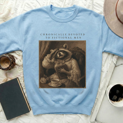 Light blue sweatshirt with a vintage raccoon artwork and text "CHRONICALLY DEVOTED TO FICTIONAL MEN."