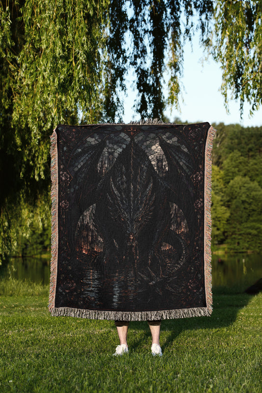 A person standing in a grassy field, partially obscured by a large, dark-colored blanket featuring a dragon design.