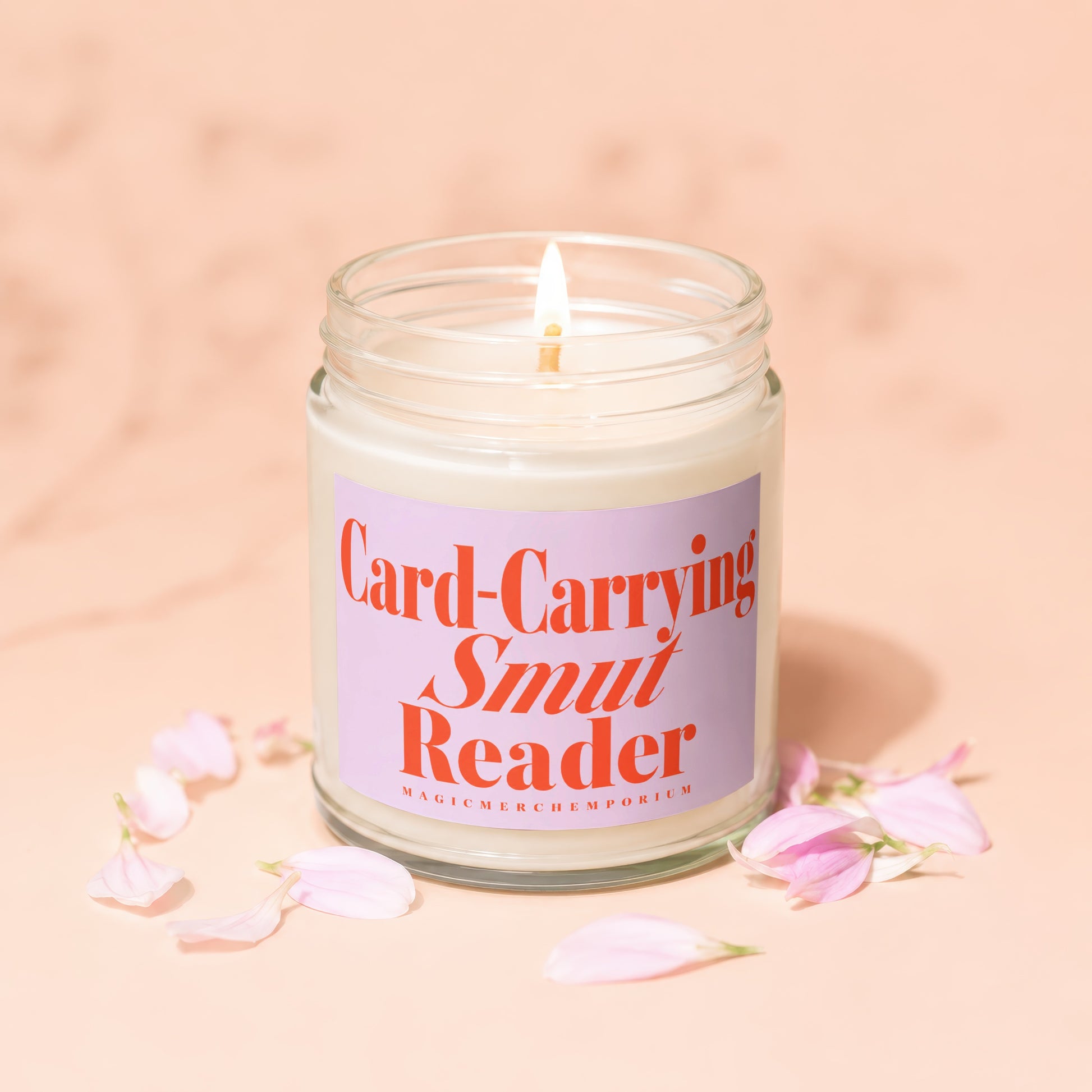 Jar candle with a lit wick and a purple label reading "Card-Carrying Smut Reader."