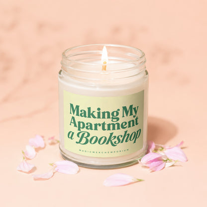 Lit candle in jar with label "Making My Apartment a Bookshop." and petal accents.