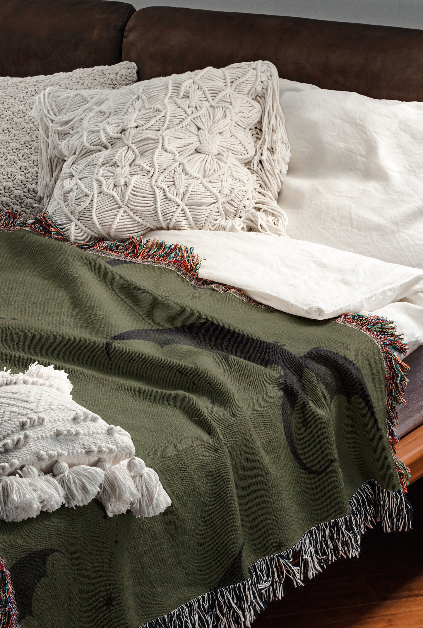a cozy and inviting bedroom scene, featuring a bed with a green blanket and white pillows, a brown leather couch, and a wooden floor.