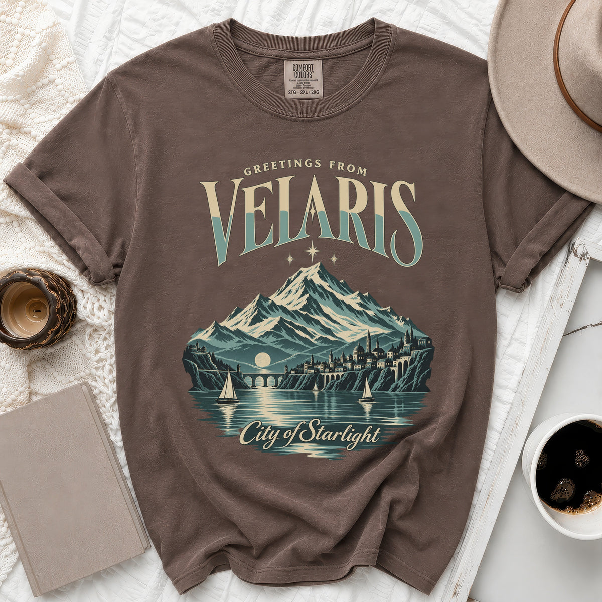 Brown t-shirt with "Greetings from Velaris City of Starlight" graphic.