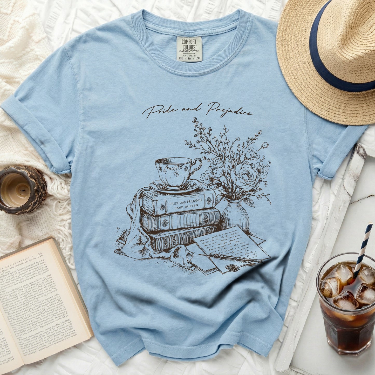 Light blue t-shirt with Pride and Prejudice books, teacup, and floral design.