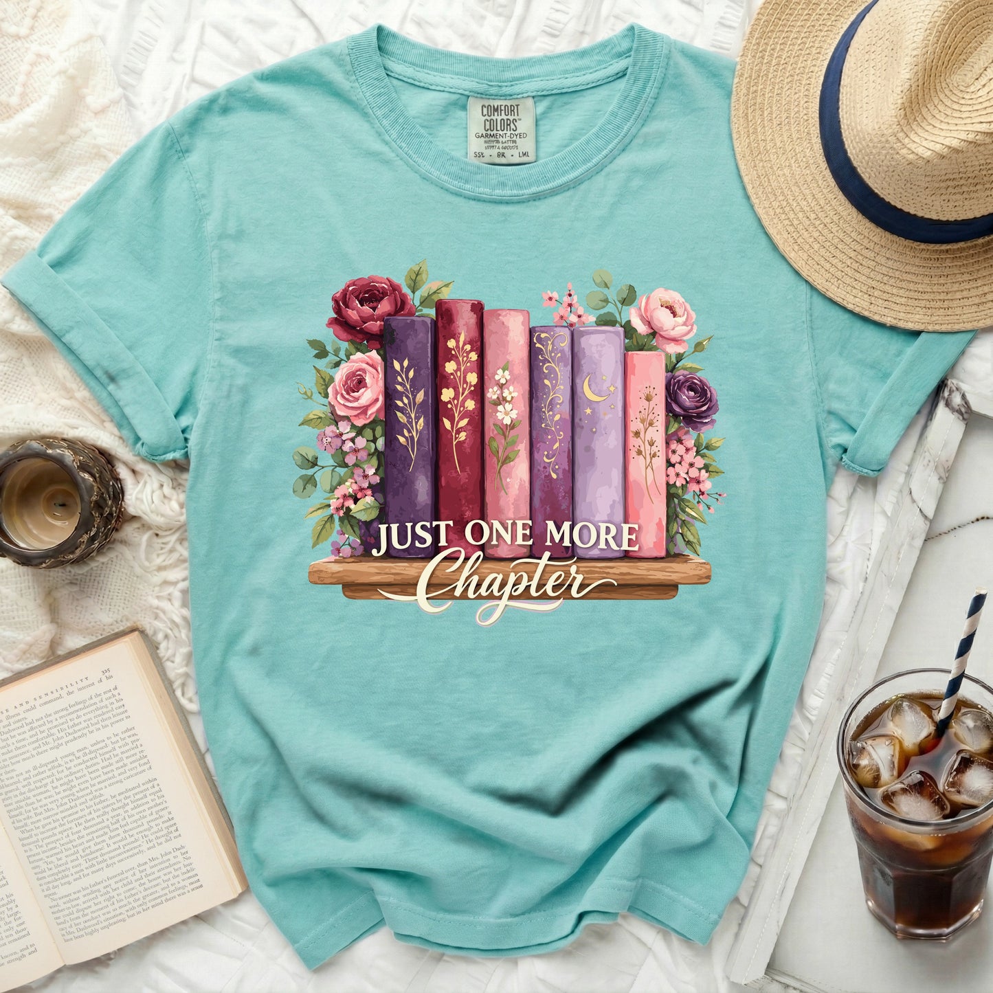 Teal t-shirt with "Just One More Chapter" book and floral graphic.