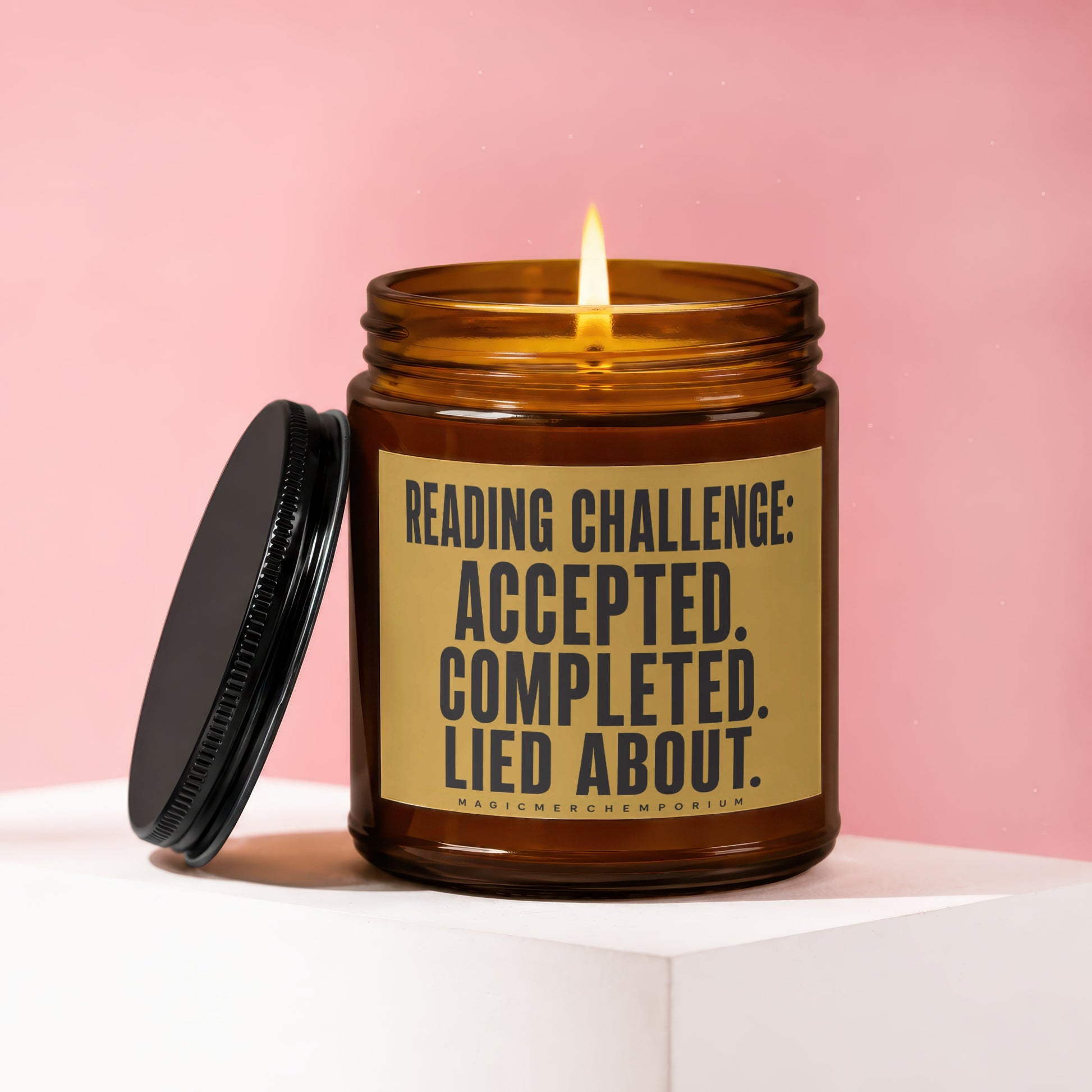 Amber jar candle with burning wick and black lid, reading "Reading Challenge: Accepted. Completed. Lied About."