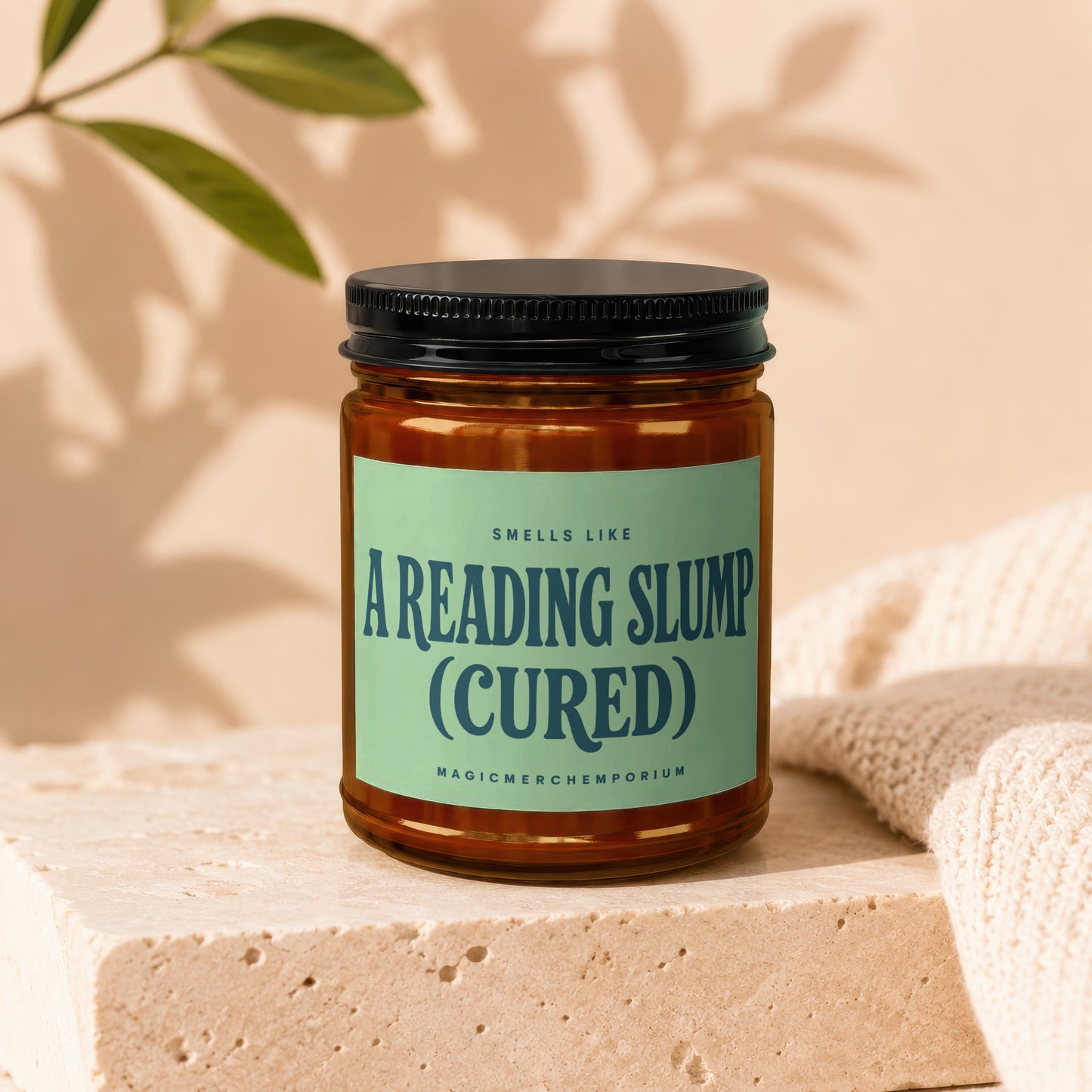Amber jar candle with light green label reading "Smells Like a Reading Slump (Cured)".