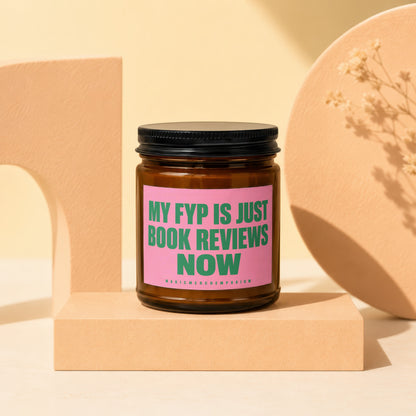 Brown glass candle with pink label reading "MY FYP IS JUST BOOK REVIEWS NOW".