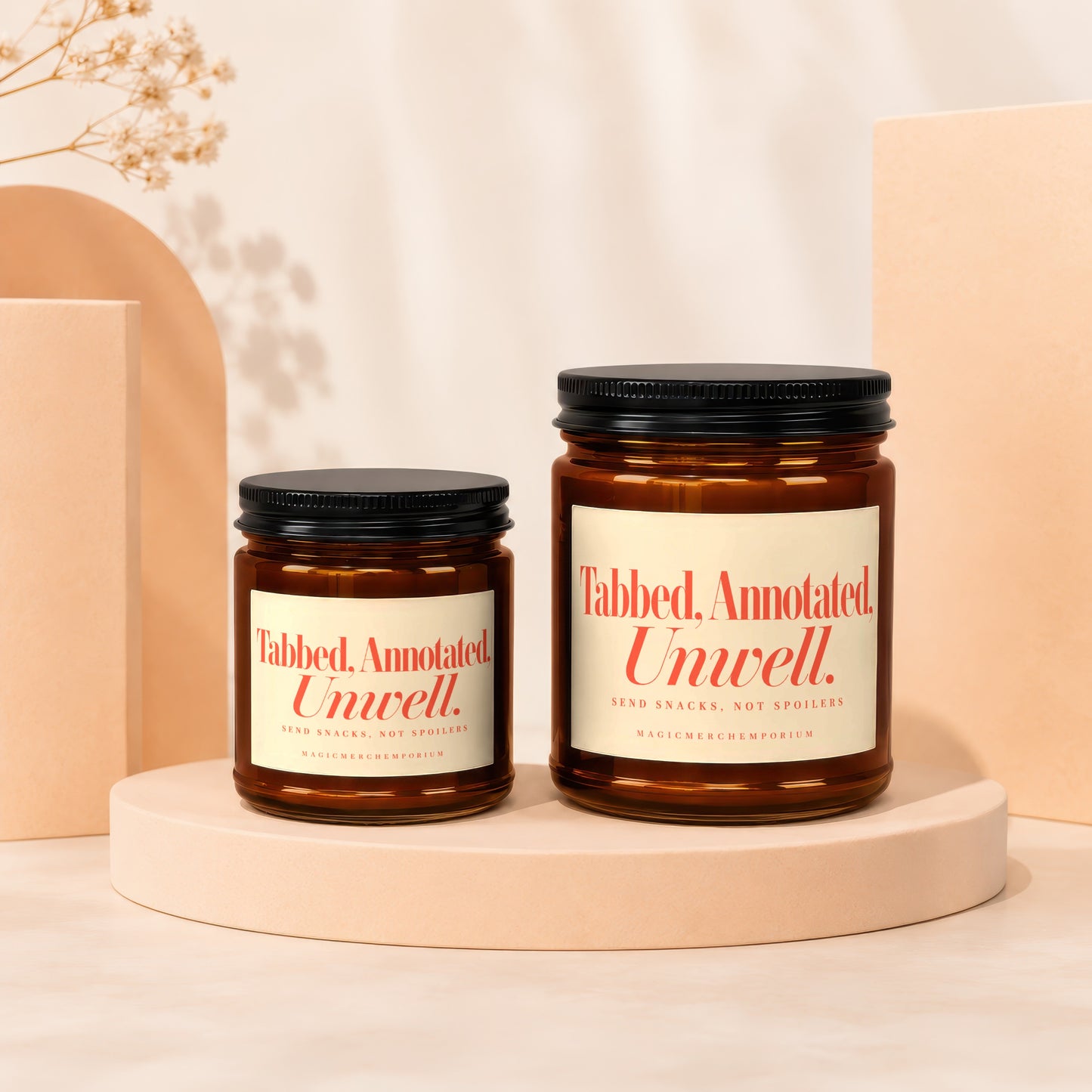 Two amber glass candles with black lids and cream labels saying "Tabbed, Annotated. Unwell.".