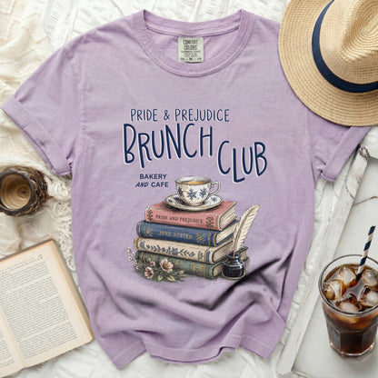 Purple t-shirt with "Pride & Prejudice Brunch Club" graphic and stack of books.