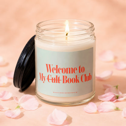 Glass candle with lit wick, lid ajar, reads "Welcome to My Cult Book Club".