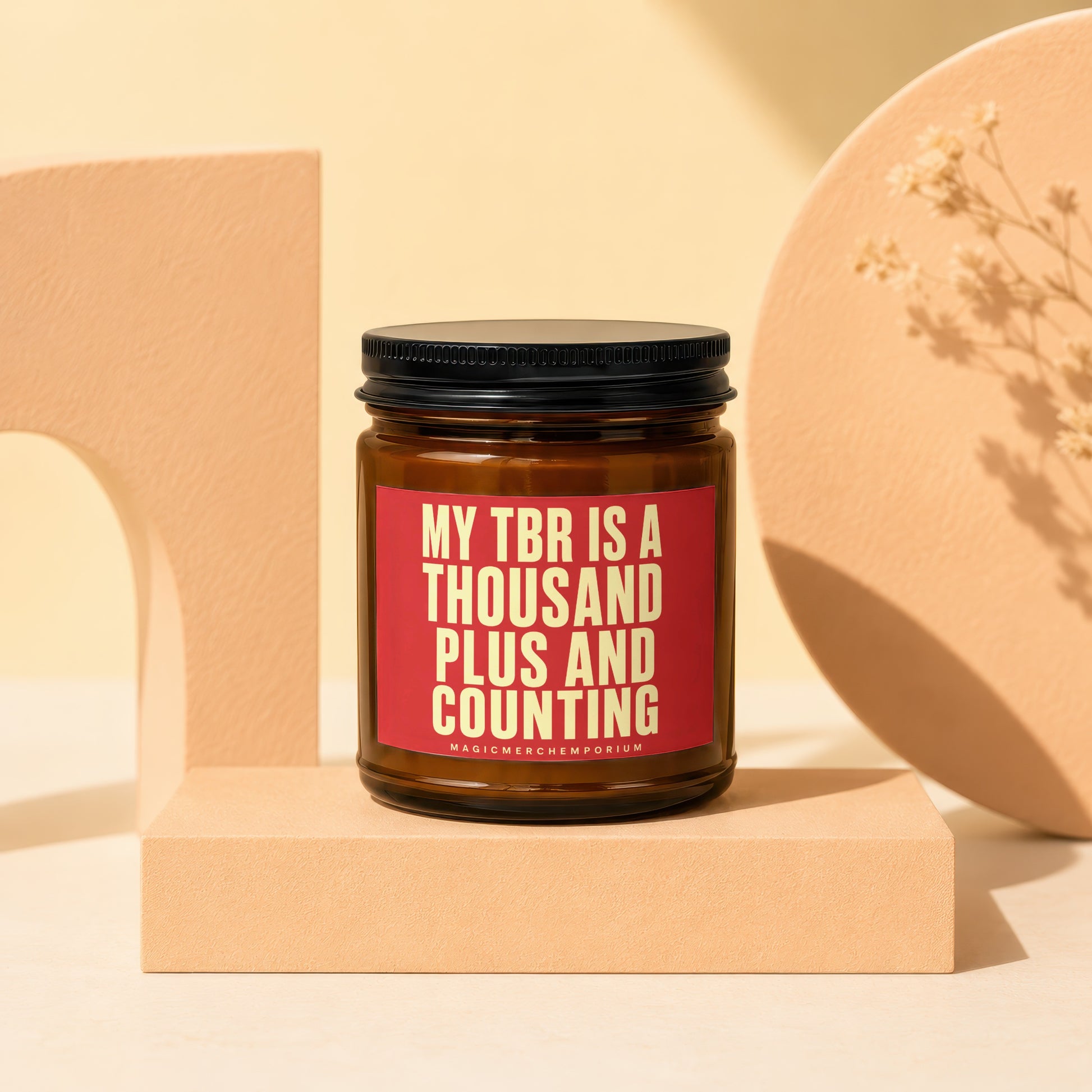 Amber jar candle with red label reading "MY TBR IS A THOUSAND PLUS AND COUNTING".