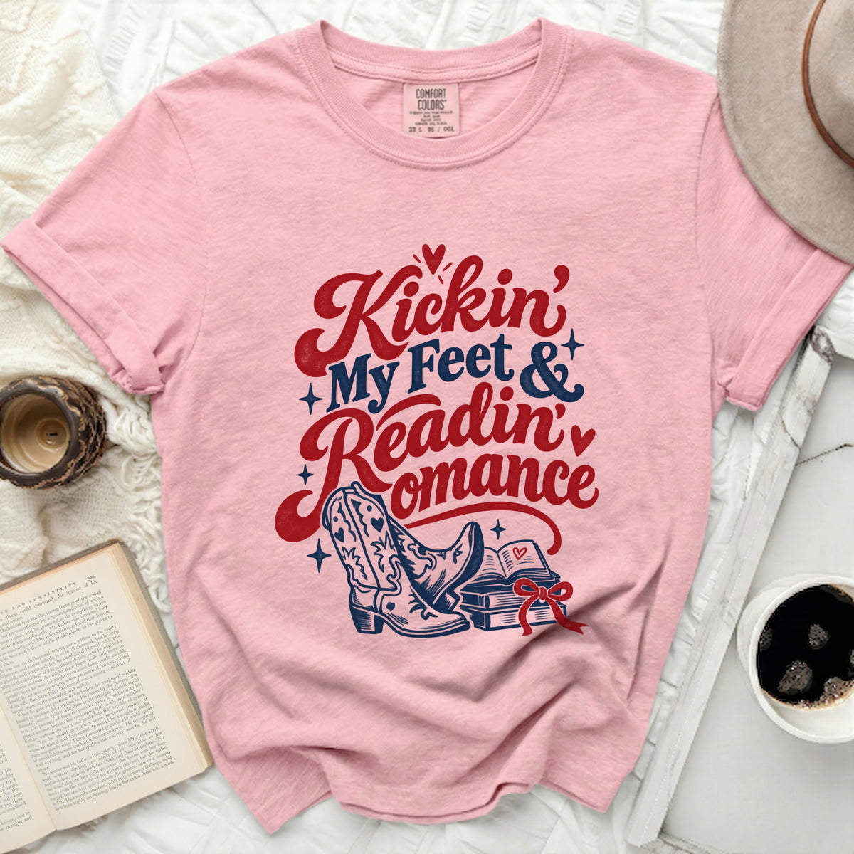 Pink t-shirt with "Kickin' My Feet & Readin' Romance" text and cowboy boots.