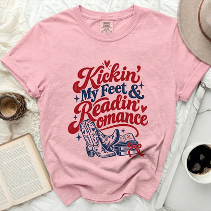 Pink t-shirt with "Kickin' My Feet & Readin' Romance" text and cowboy boots.