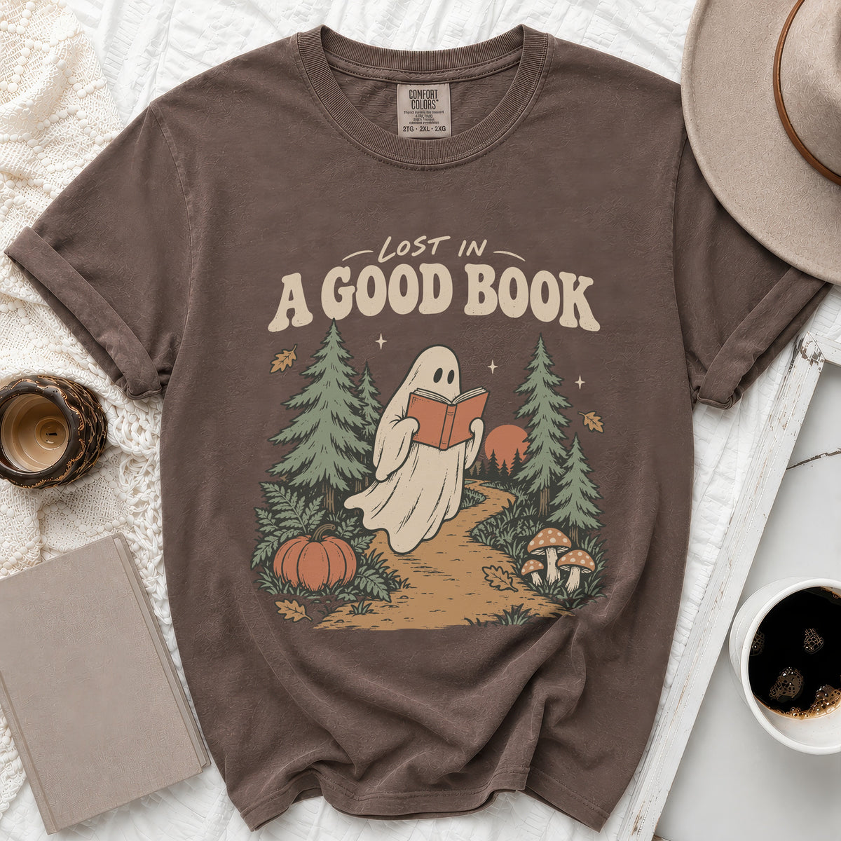 Brown t-shirt with a ghost reading "Lost in a Good Book" amidst trees.