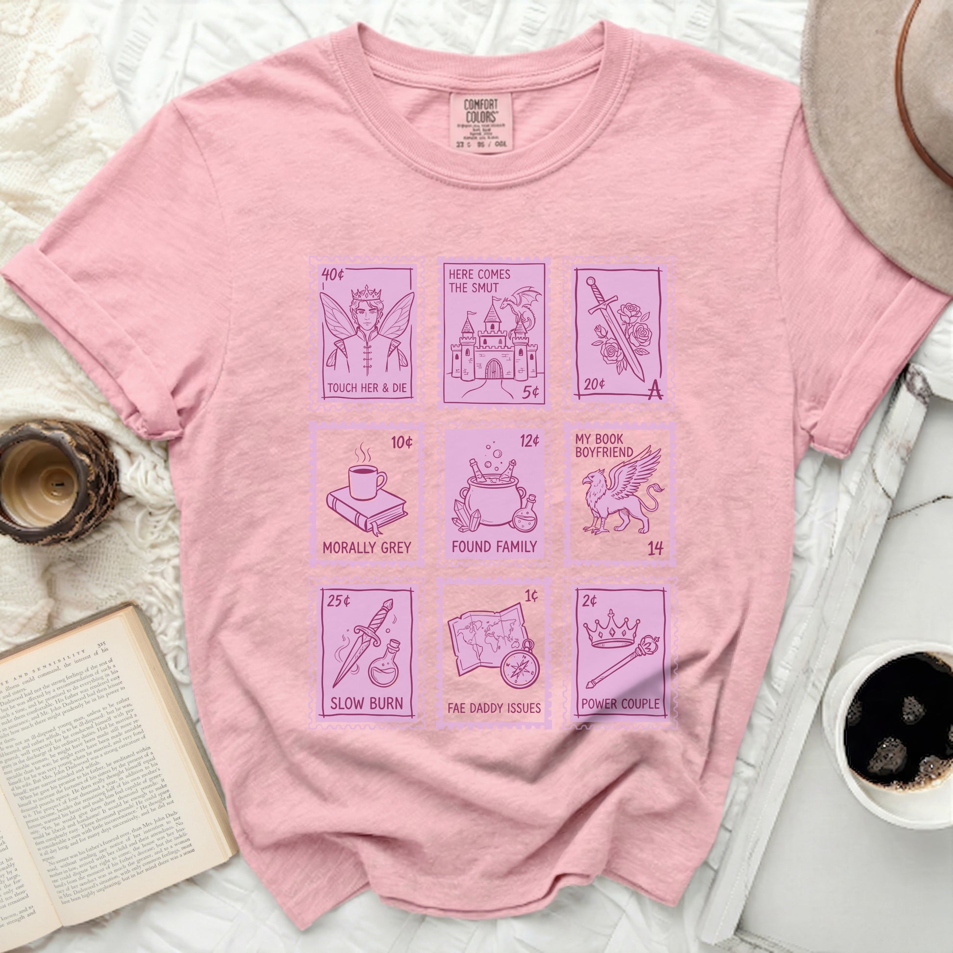 Pink Comfort Colors t-shirt with postage stamp designs and text about romance tropes.