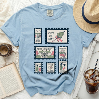 Light blue t-shirt with postage stamp designs featuring book titles and illustrations.